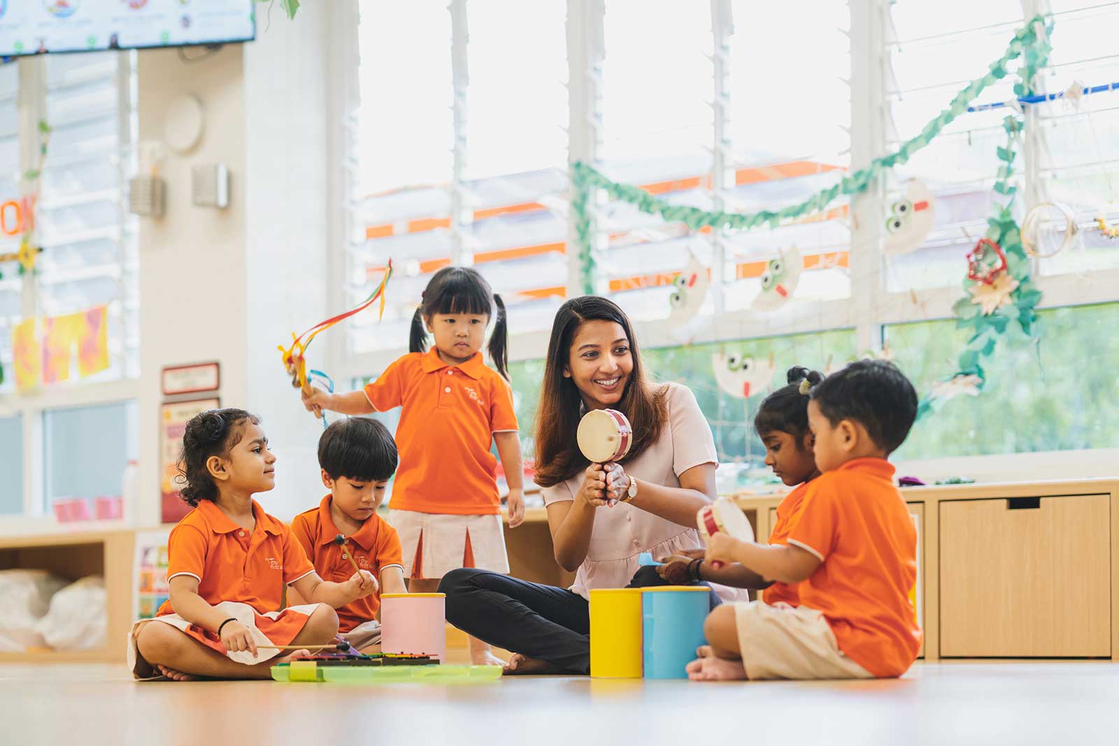 A My First Skool teacher leading a group of children in a music activity